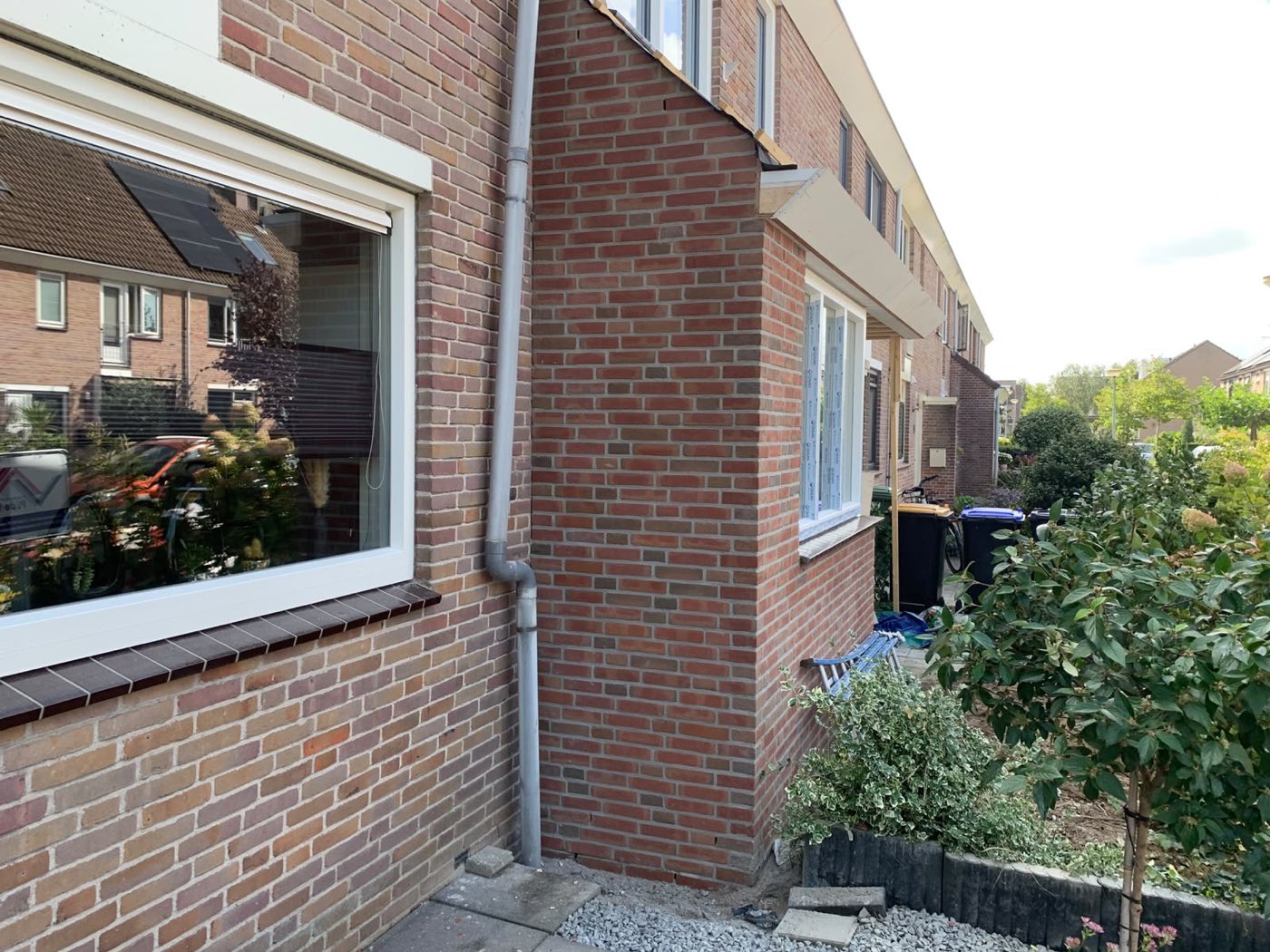 Gemetselde aanbouw met een nieuw raam, aansluitend op de gevel
