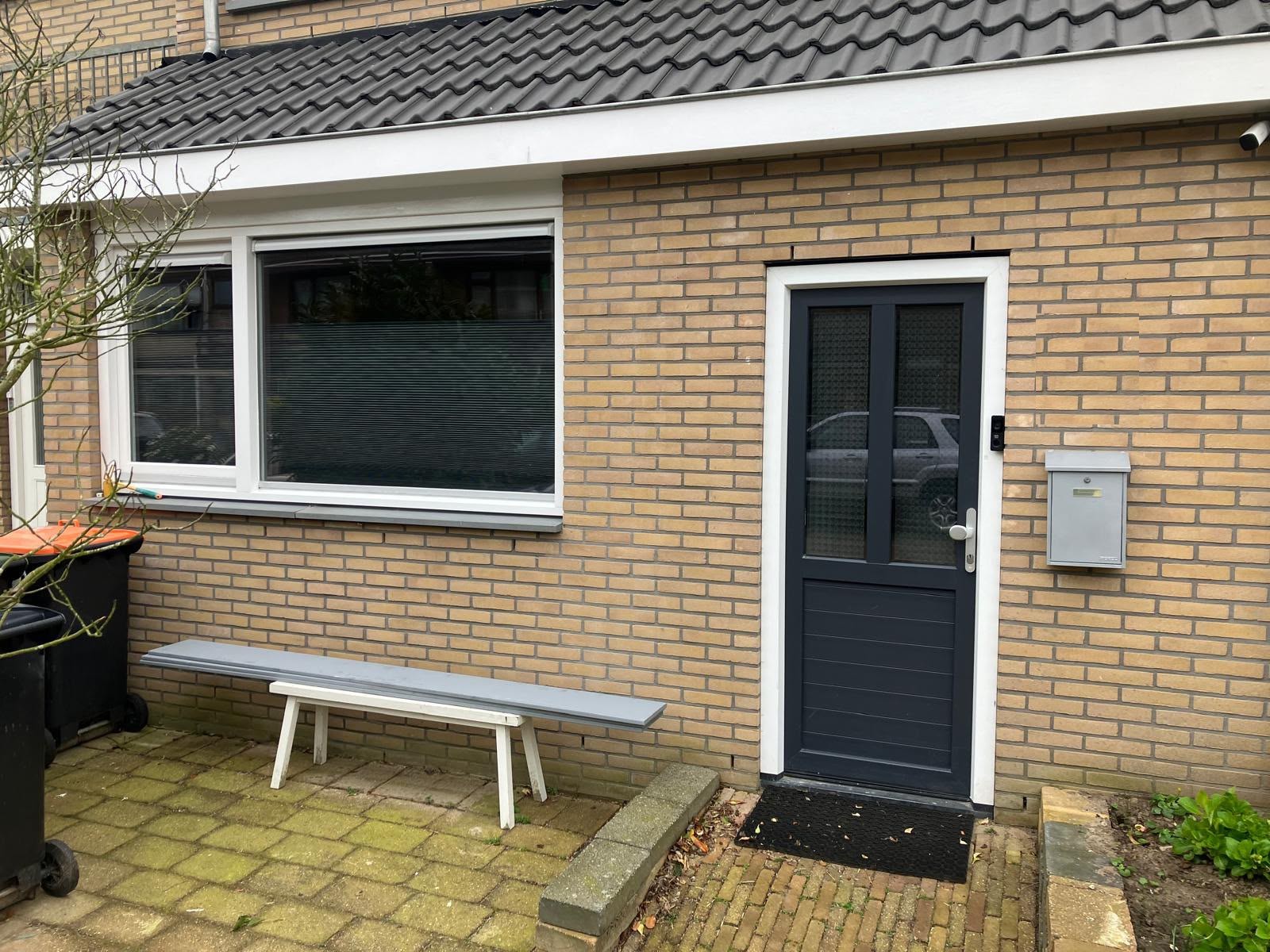 Gevel van gele baksteen met een nieuwe voordeur en raam