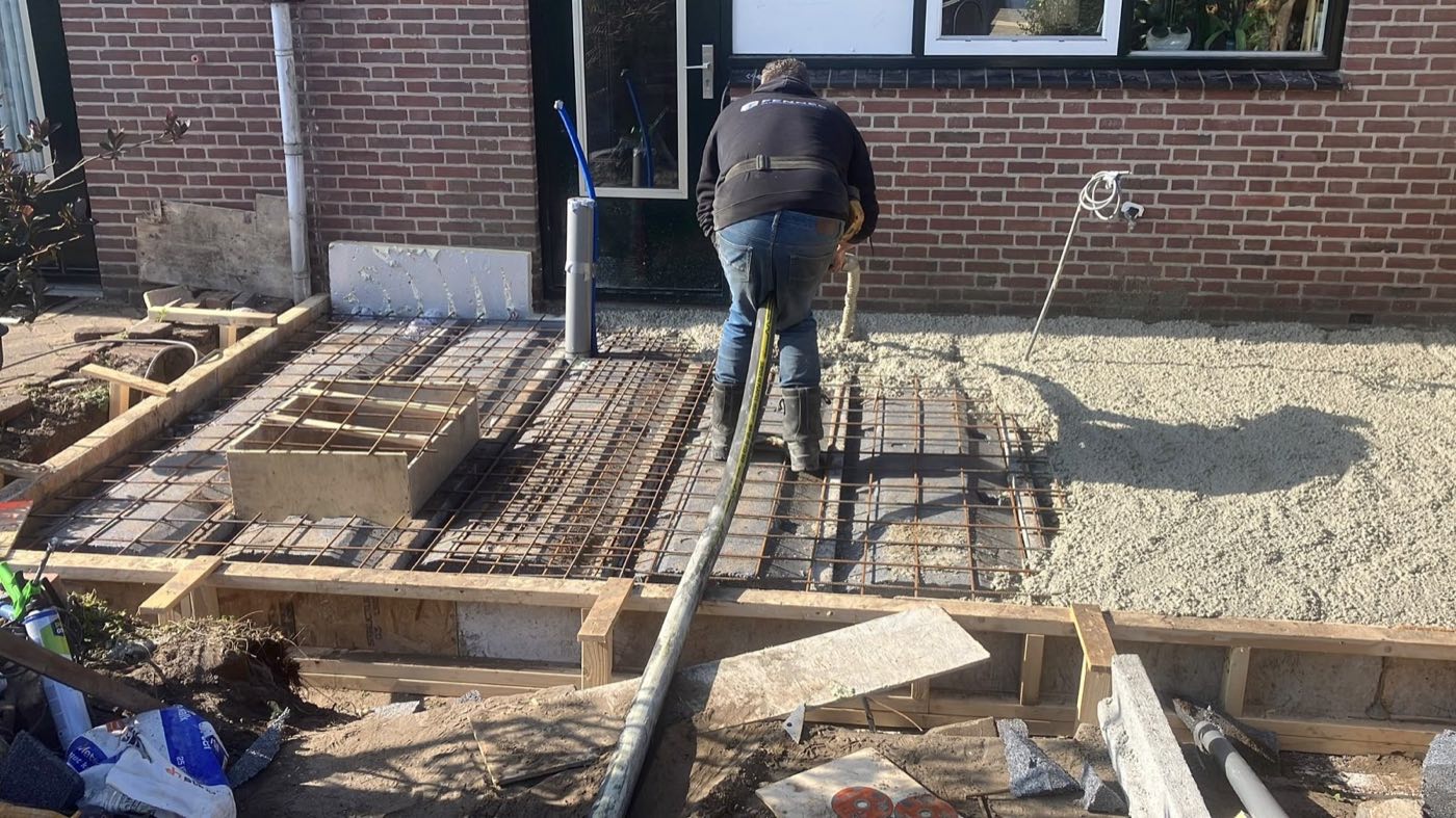 Op de bouw: de vloer van een uitbouw wordt gestort, met wapening en bekisting