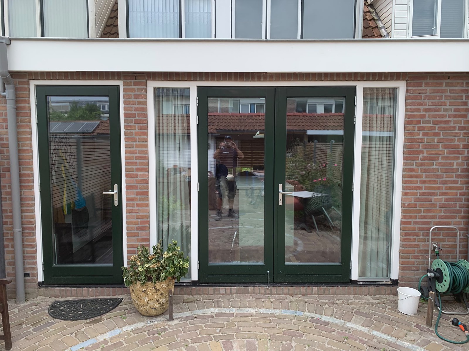 Afgeronde uitbouw met donkergroene openslaande deuren en zijlichten