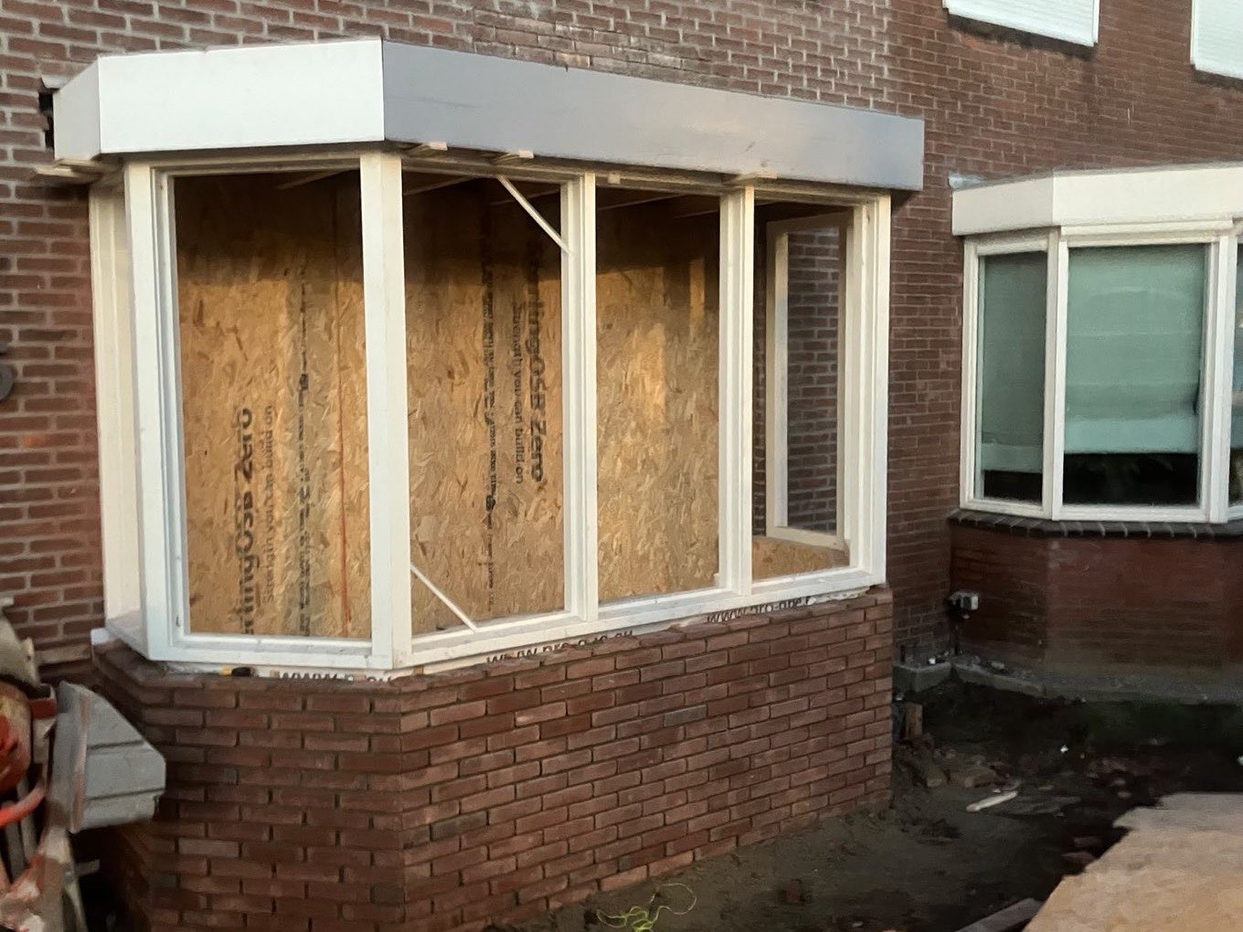 Uitbouw in aanbouw met nieuwe kozijnen en een gemetselde borstwering